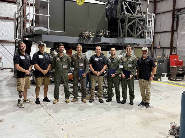 Full class photo in front of large UH-60 simulator