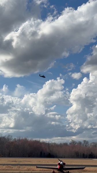 UH-60 in flight over airport with small plane