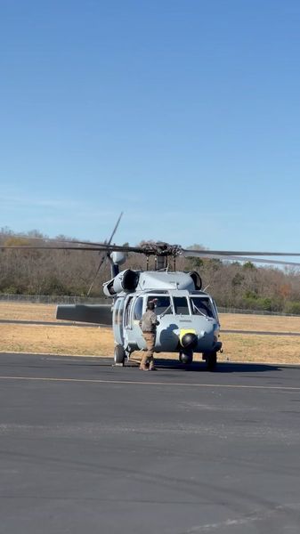 Grey UH-60 on ramp, crew standing by