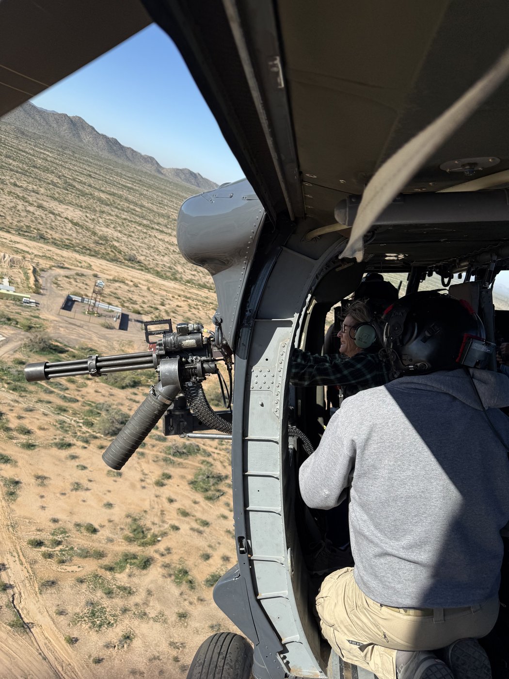 Crew at Black Hawk doorway with weapon, desert below
